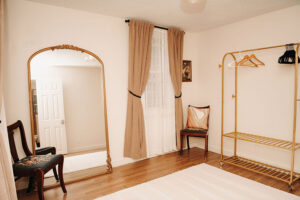 Dressing area with gold framed, full length mirror, clothes rack and chairs in Bridal Cottage at Country Villa Weddings and Events.