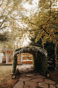 Foliage tunnel entrance to the pavilion with stone pathway at Country Villa Weddings and Events.