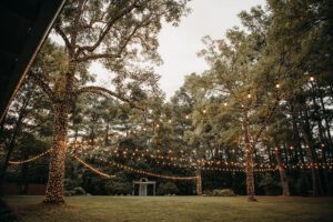 Overall view of the altar area with a canopy of lighted trees at Country Villa Weddings and Events.