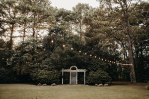 White, lattice altar with an awning of string lights overhead at Country Villa Weddings and Events.