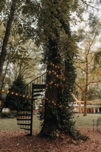 Spiral, black iron staircase, nestled among lighted trees at Country Villa Weddings and Events.