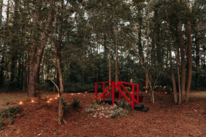 Red bridge surrounded by trees and white lights; great photo-op space at Country Villa Weddings and Events.